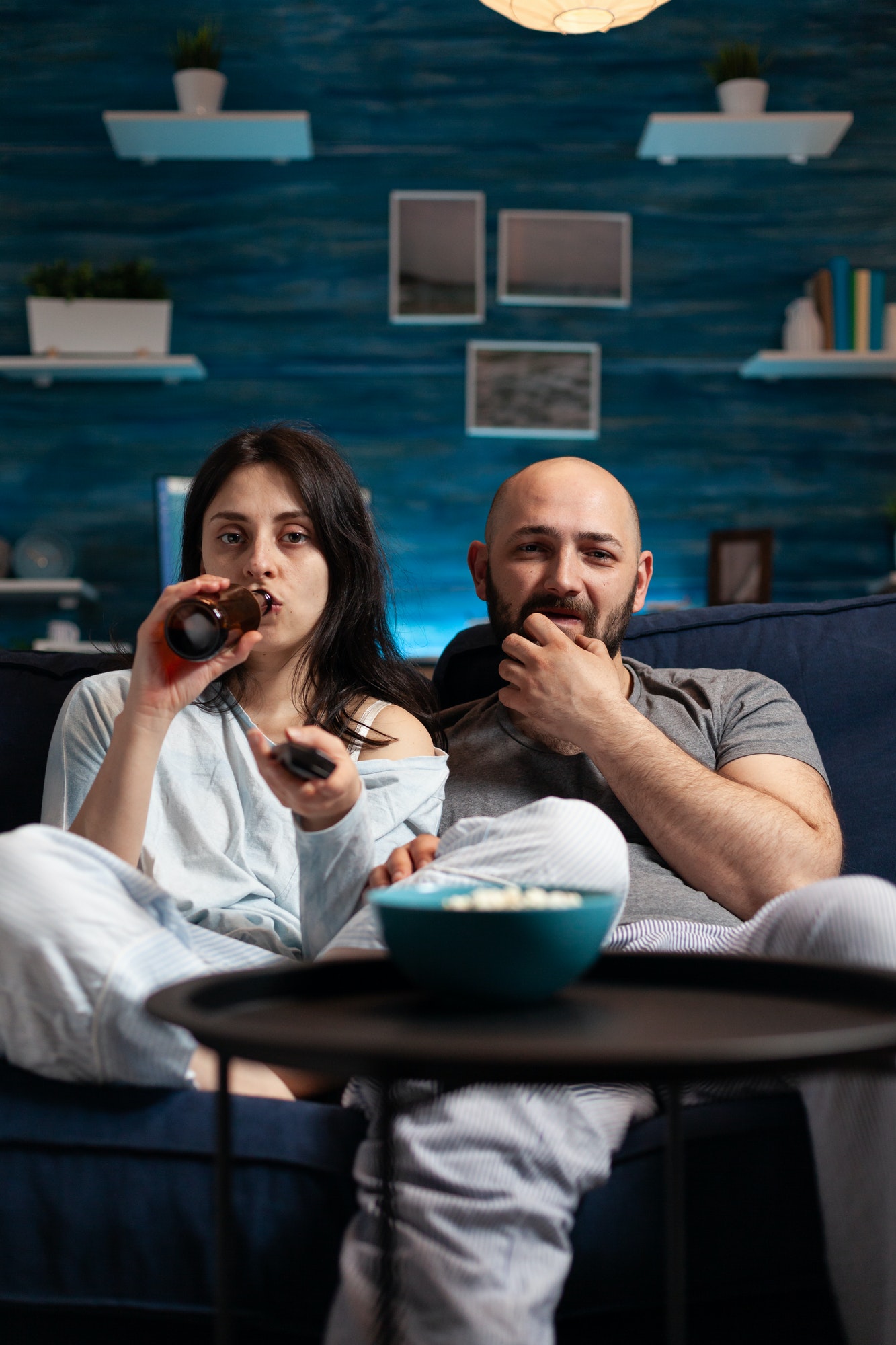 Relaxed excited couple watching TV on couch relaxing late at night